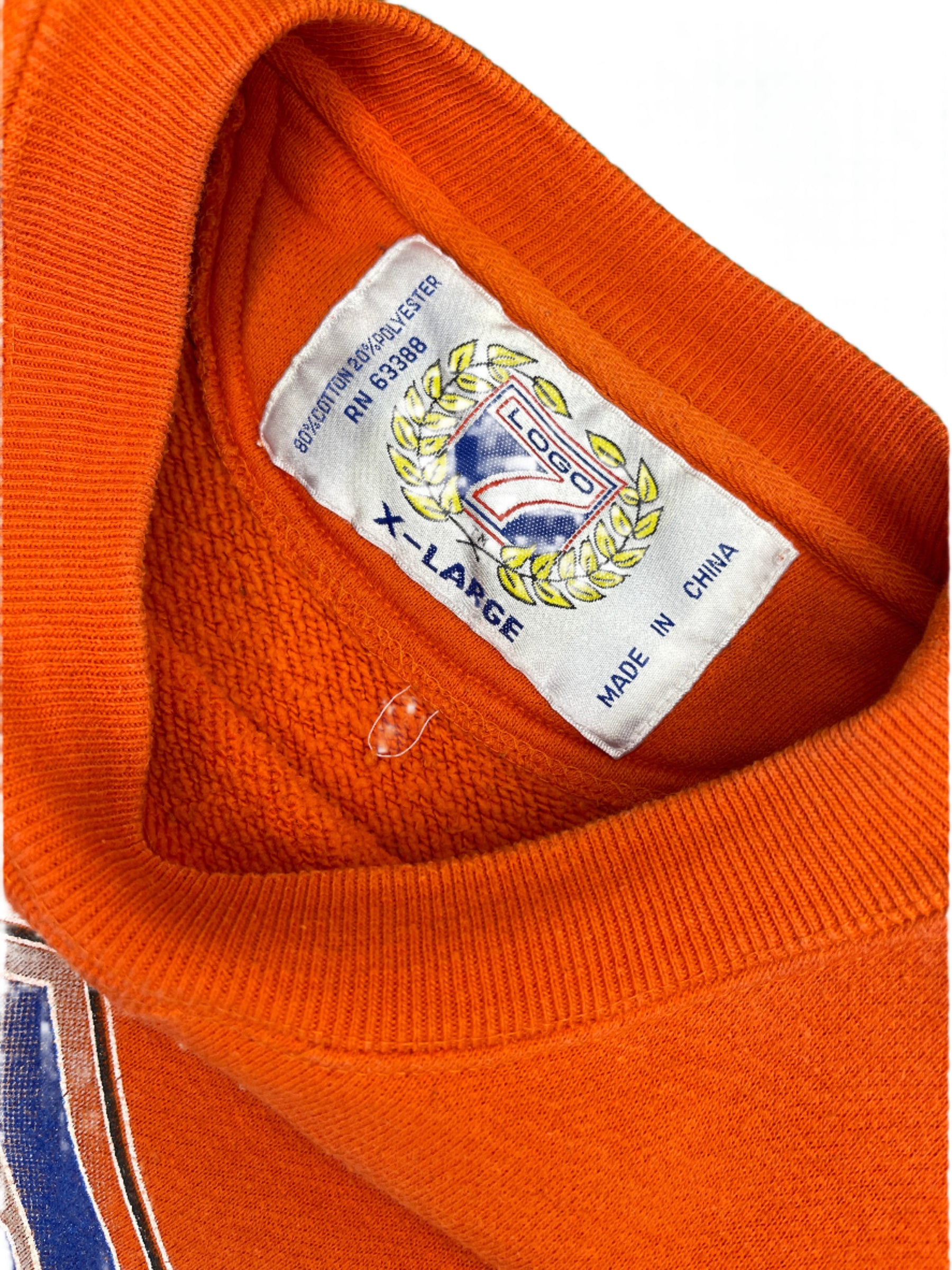 Close-up of an orange sweatshirt with a brand label on a green background